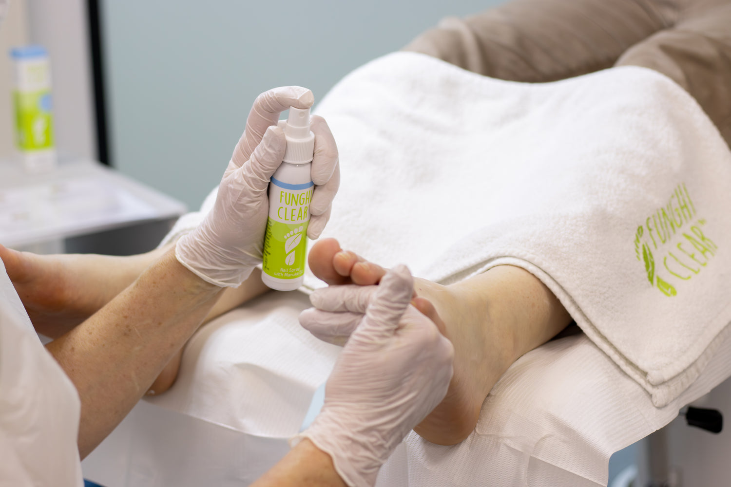 Footcare professional applying FunghiClear® nail spray to treat toenail fungus during a clinic appointment